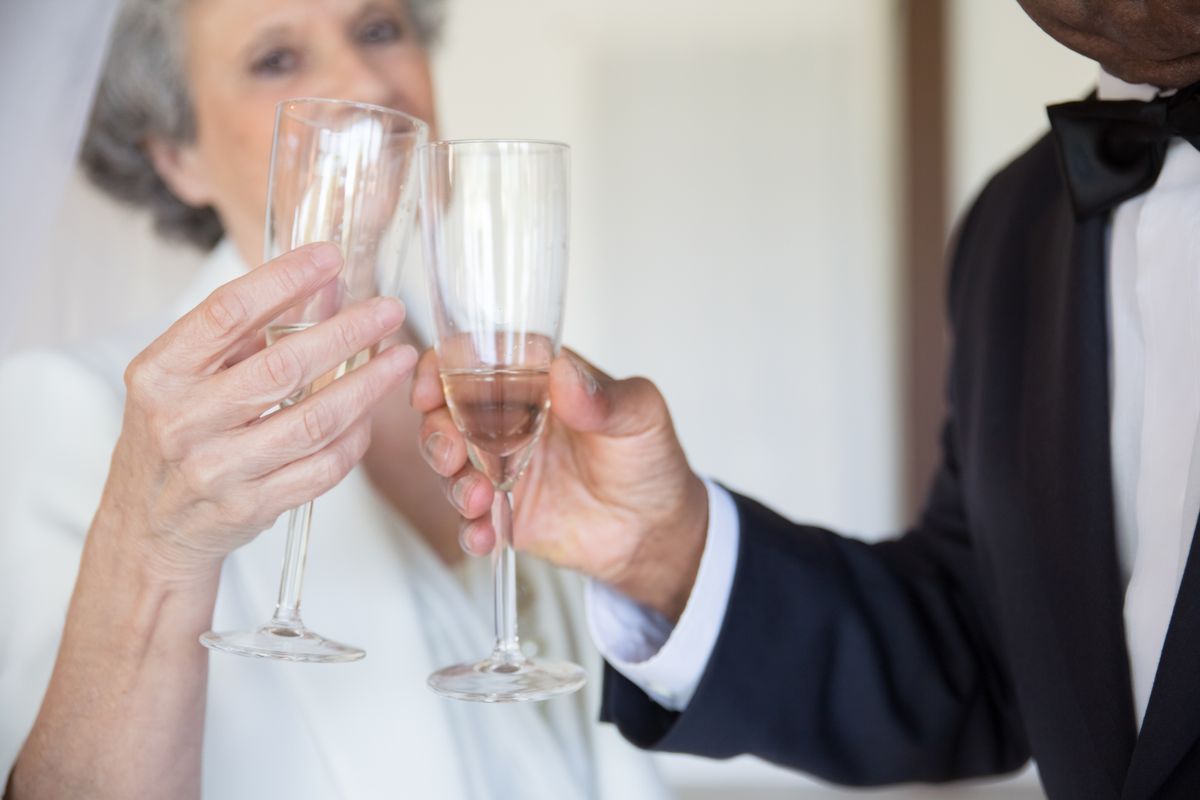 Pareja mayor brindando con copas para celebrar su historia compartida; imagen referencial
