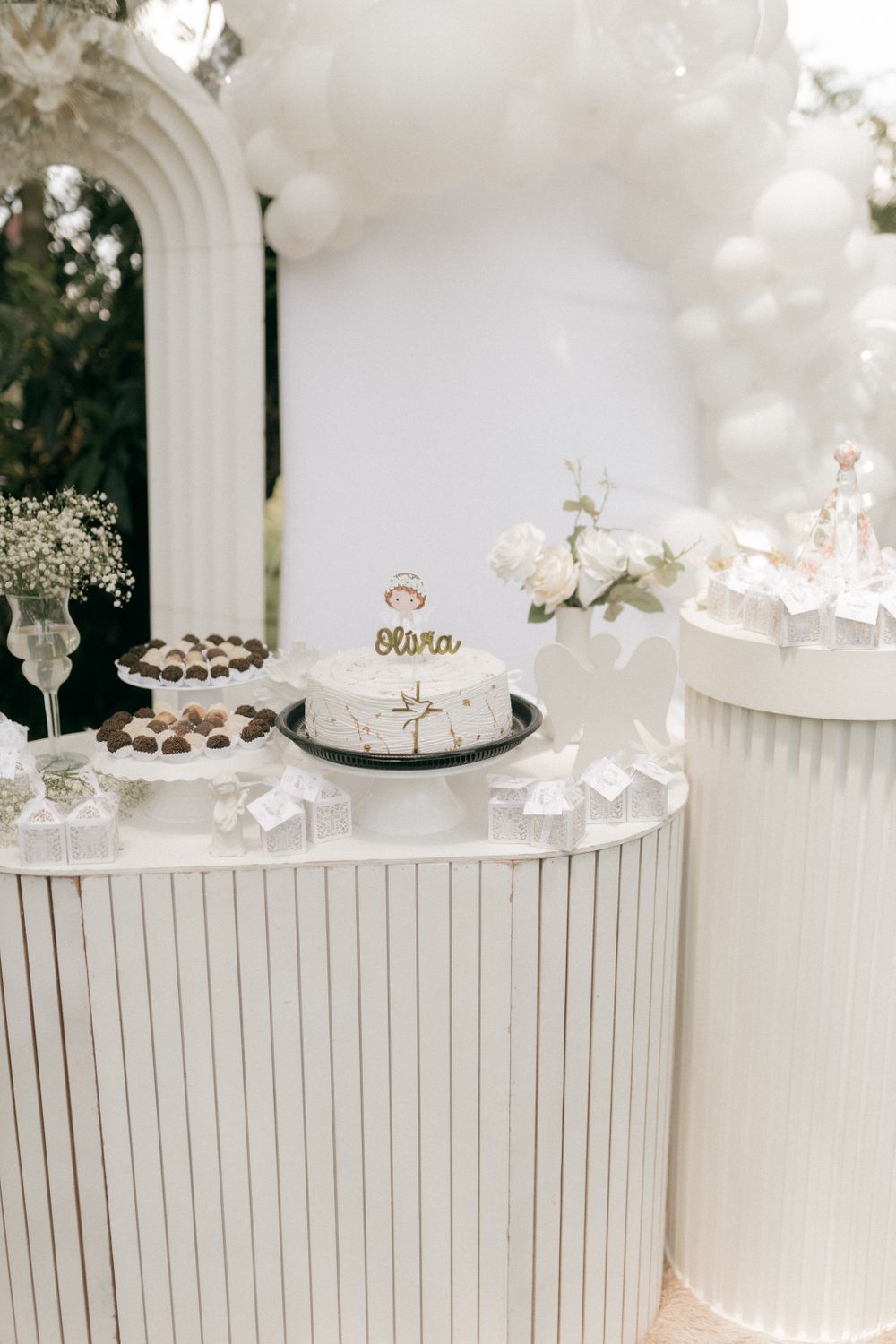 Mesa de bautizo con torta, flores y decoración blanca; imagen referencial