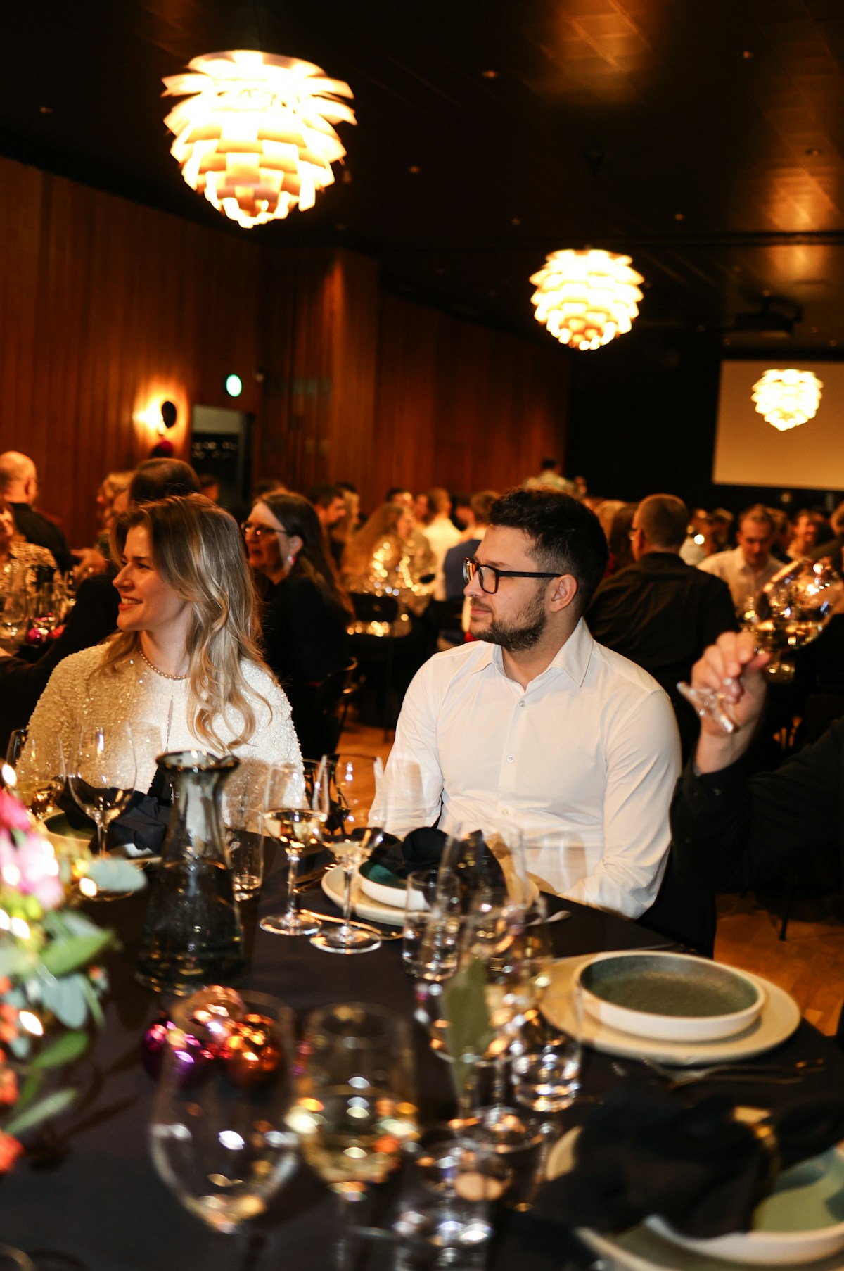 Invitados reunidos en una cena formal con mesas servidas; imagen referencial de un evento corporativo
